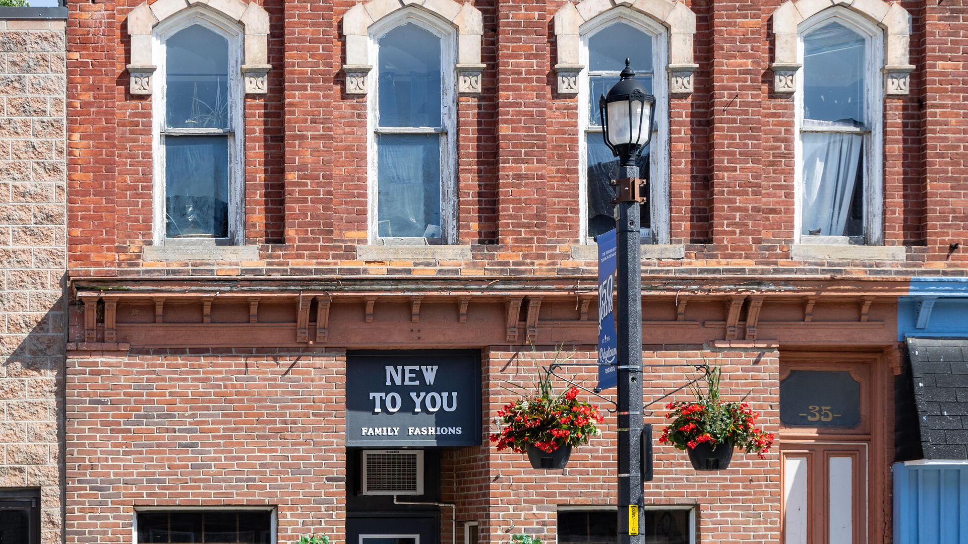 Storefront of an independently owned small-town Ontario shop, New To You Family Fashions, in a heritage brick building.