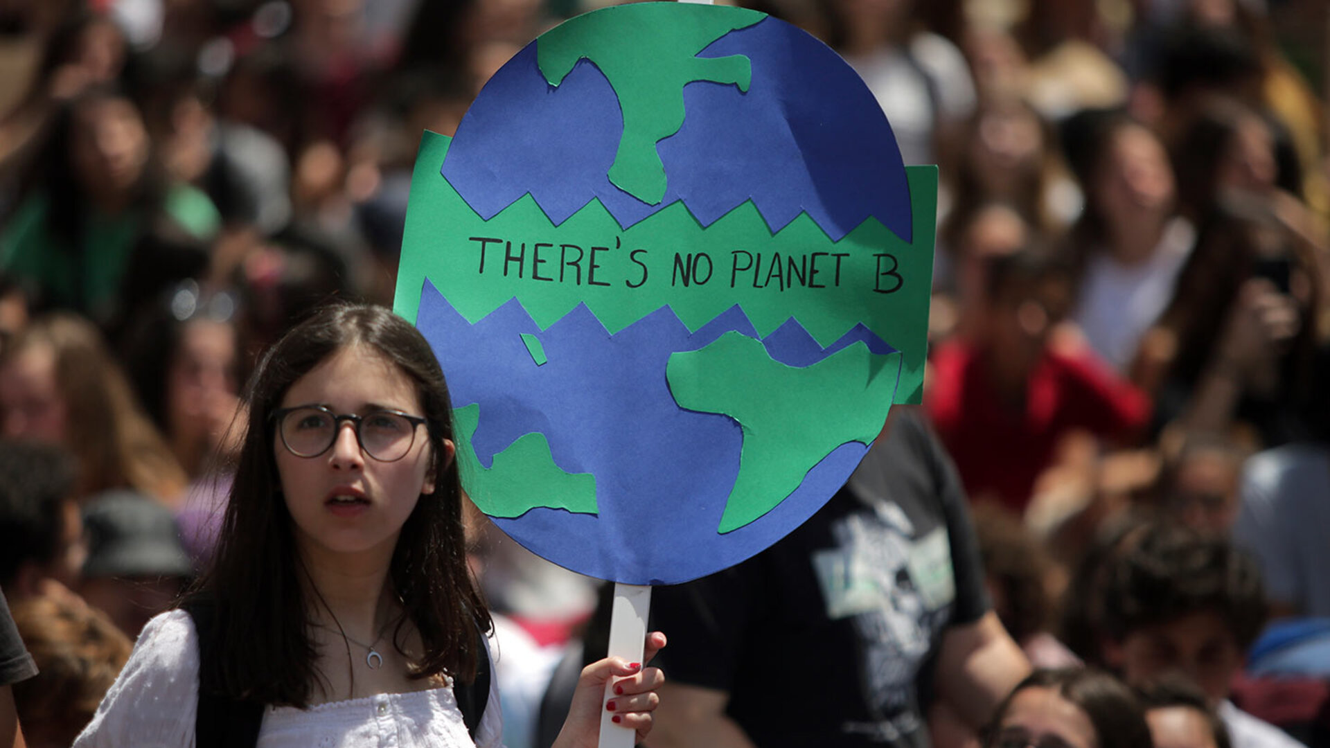A young protester holds a hand-drawn 'There's No Planet B' sign at a climate march