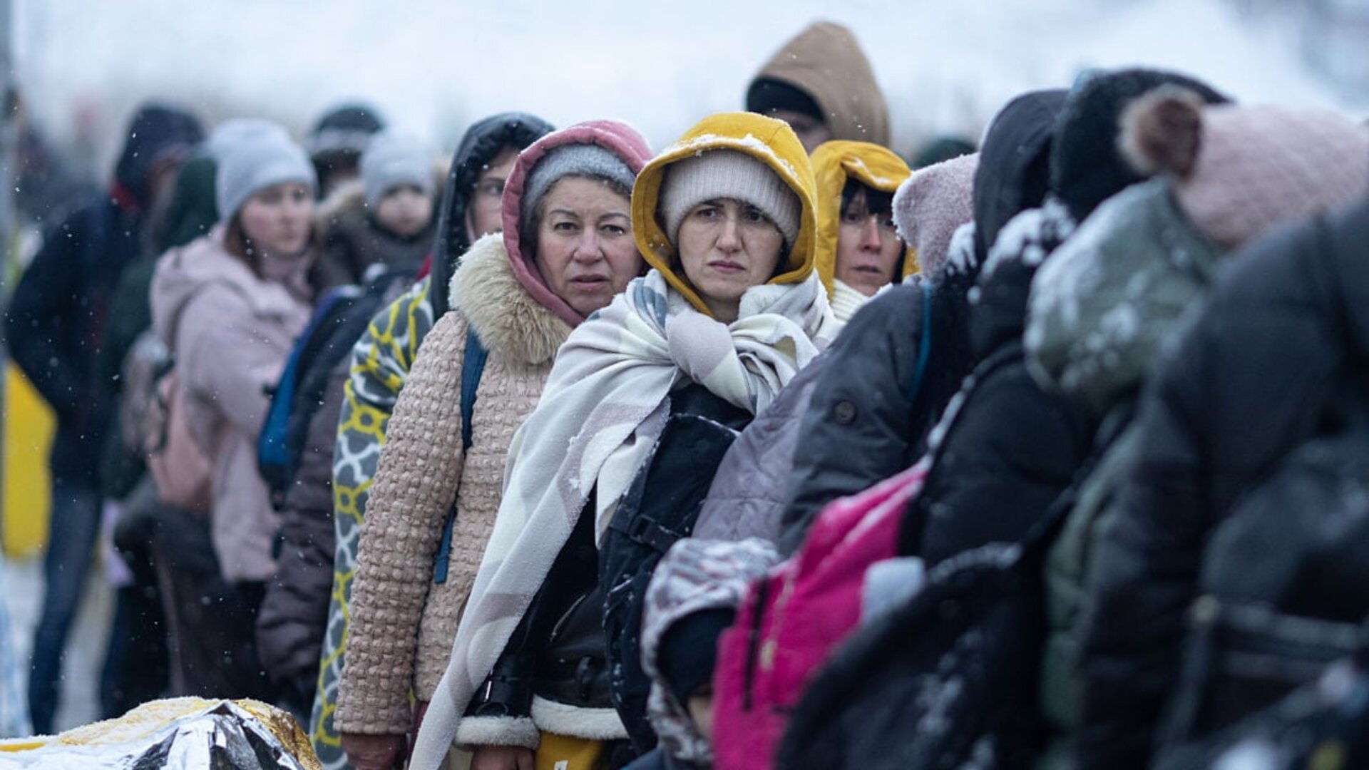 Ukrainian refugees bundled in winter coats and blankets wait in line at the Medyka border crossing from Ukraine to Poland, March 2022.