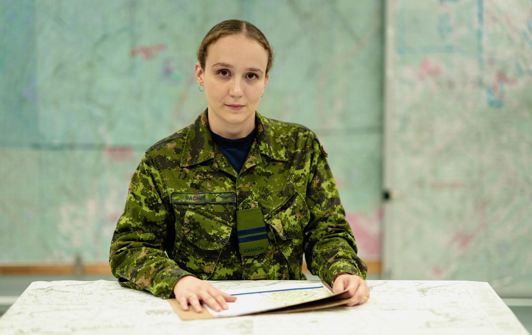A Canadian Armed Forces officer in CADPAT uniform reviewing operational maps.