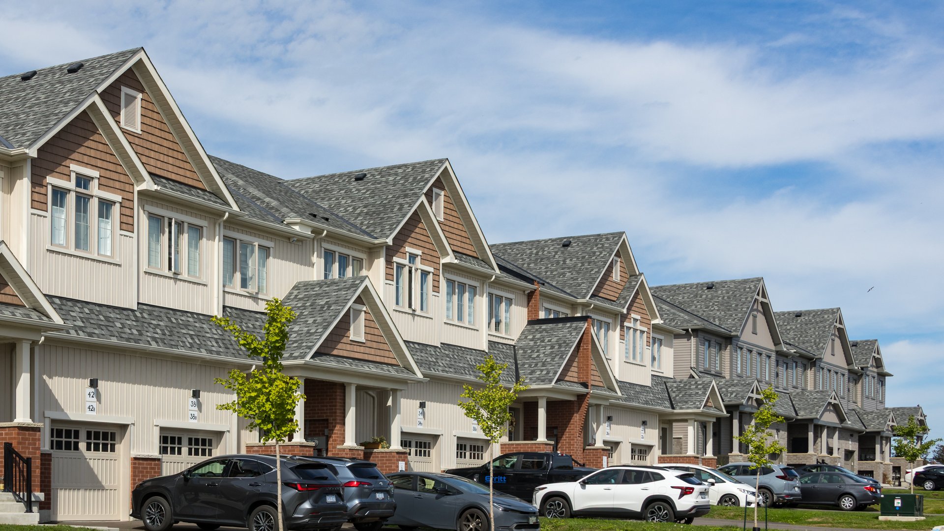 A row of new townhouses on a suburban street in Newcastle, Ontario, under a partly cloudy sky